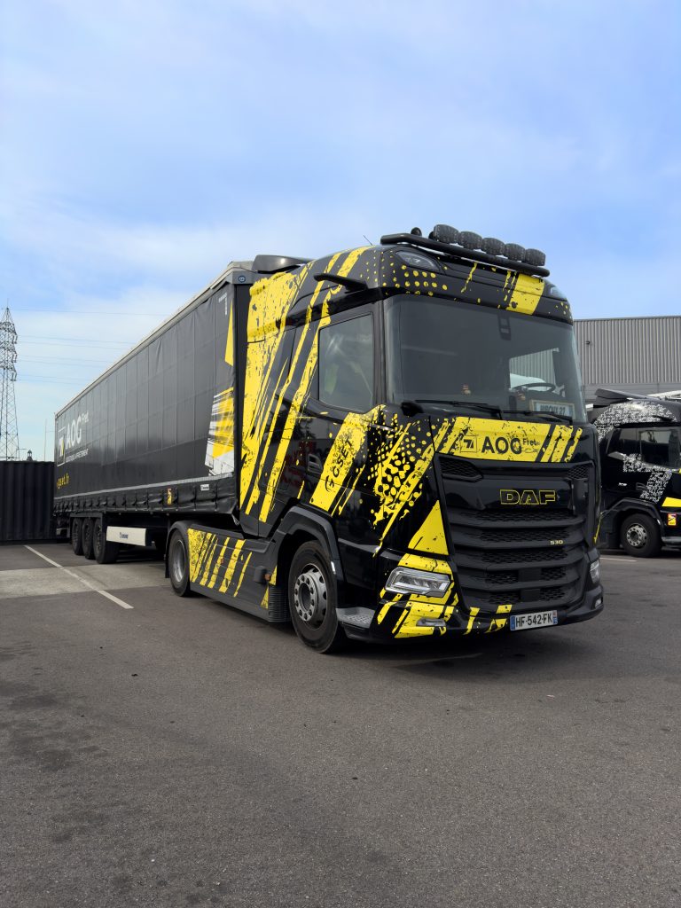 Camion DAF 530 d'AOG Fret au design noir et jaune stationné sur le site logistique, représentant la flotte de transport moderne et performante de l’entreprise.