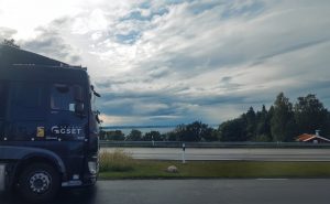Camion noir de marque GSET, stationné sur une aire de repos surplombant un lac en Suède. Le véhicule est garé sur une route, avec une forêt en arrière-plan. Transport routier longue distance.